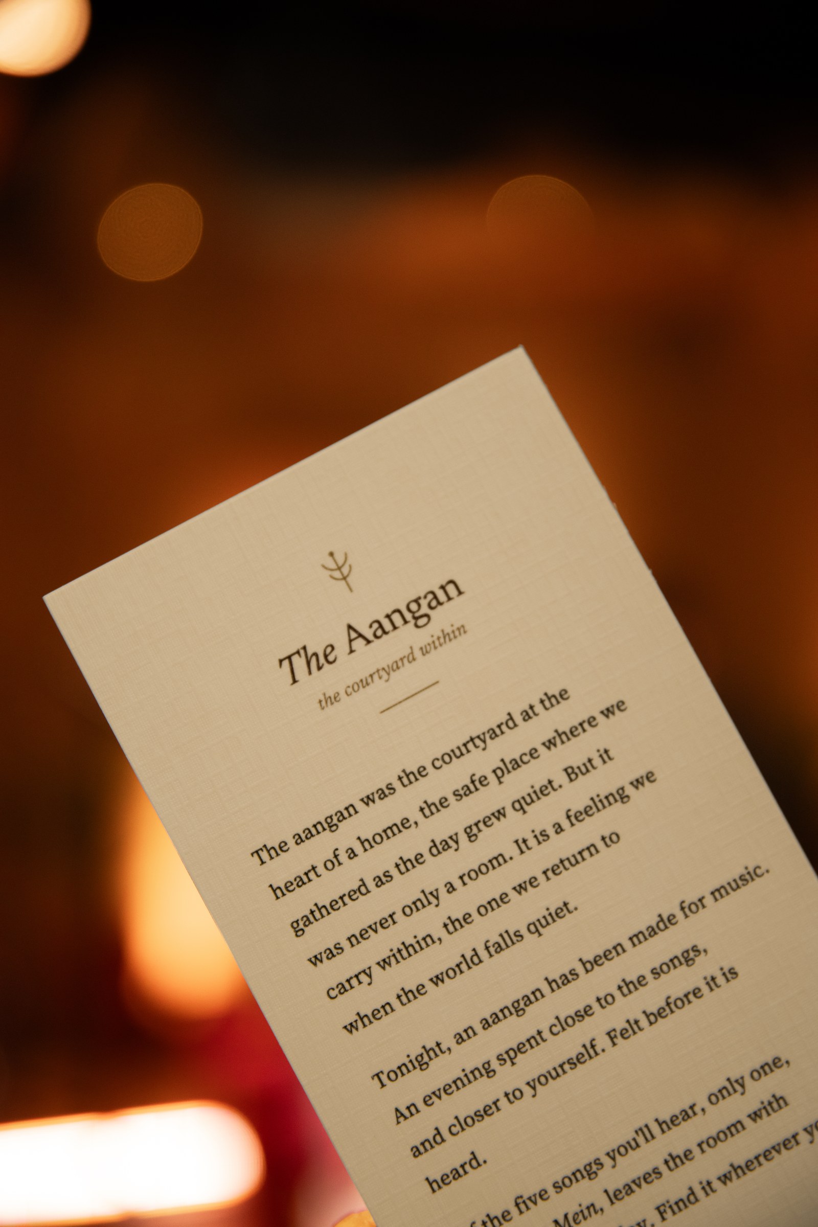 The printed concert-note card, held up in candlelight.