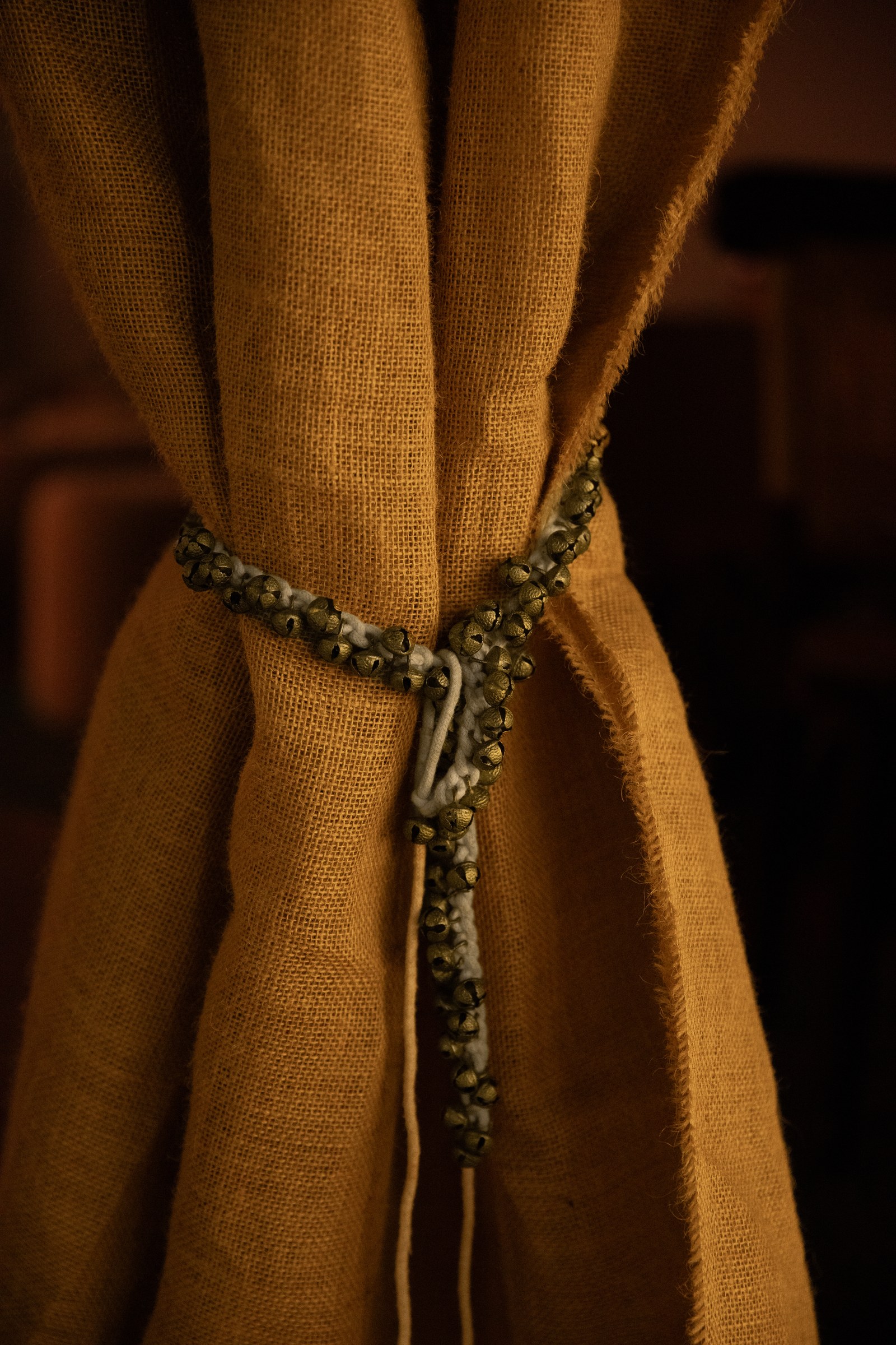 Hand-loomed cloth with brass ghungroo bells sewn in, close macro.