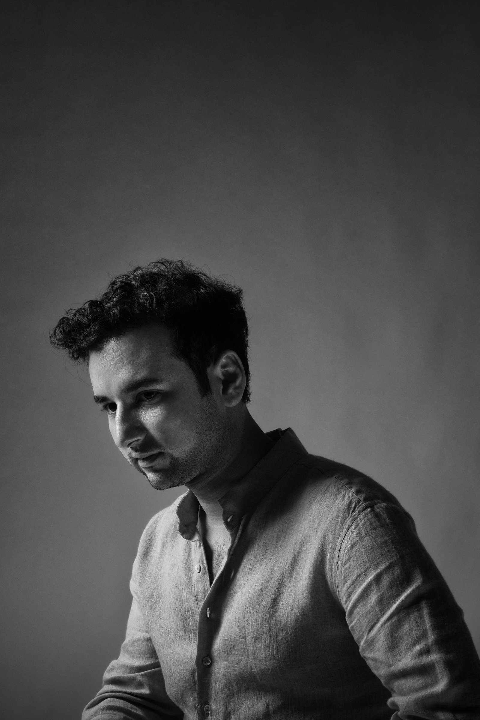 Viraj Bahri, black-and-white studio portrait, looking down, contemplative.